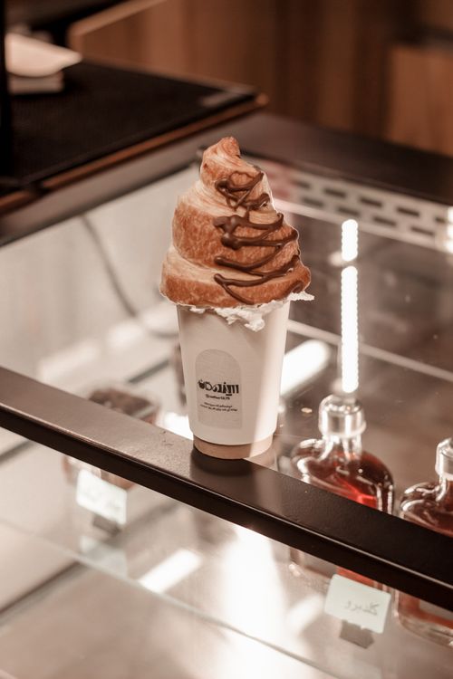 Free A rich coffee topped with a croissant swirl in a cozy Kermanshah cafe display. Stock Photo