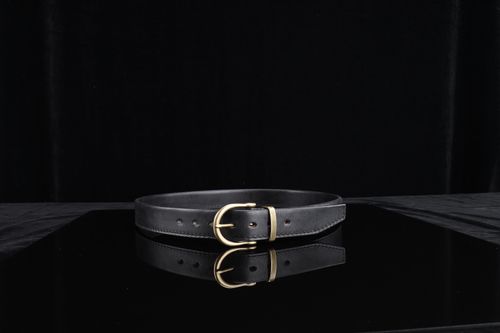 Free High-quality black leather belt with a gold buckle on a dark reflective surface, perfect for fashion statements. Stock Photo