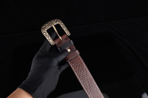 Free Close-up of a brown leather belt with intricate gold buckle held against a black background. Stock Photo