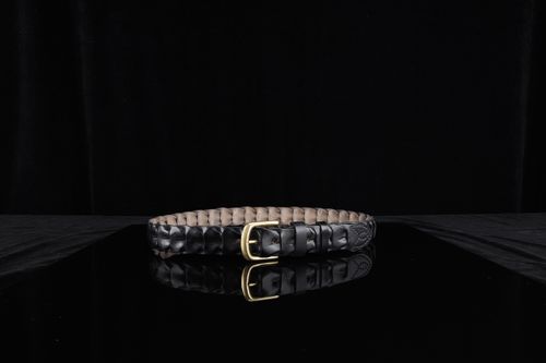 Free Stylish black leather belt with a gold buckle elegantly displayed on a reflective black surface. Stock Photo
