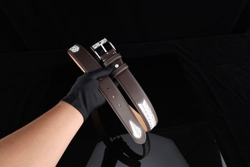 Free Stylish brown leather belt with silver detailing held by a gloved hand. Stock Photo