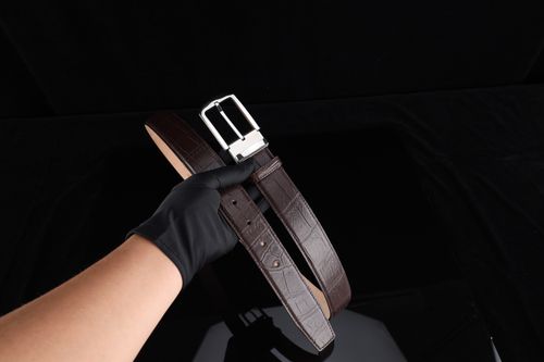 Free Stylish dark brown leather belt held by gloved hand, perfect for gifts and fashion. Stock Photo