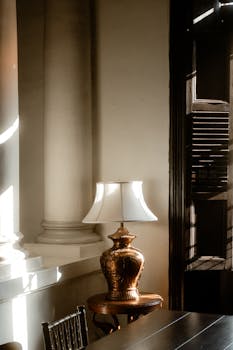 Elegant decorative lamp on wooden table against a background of classical architecture.