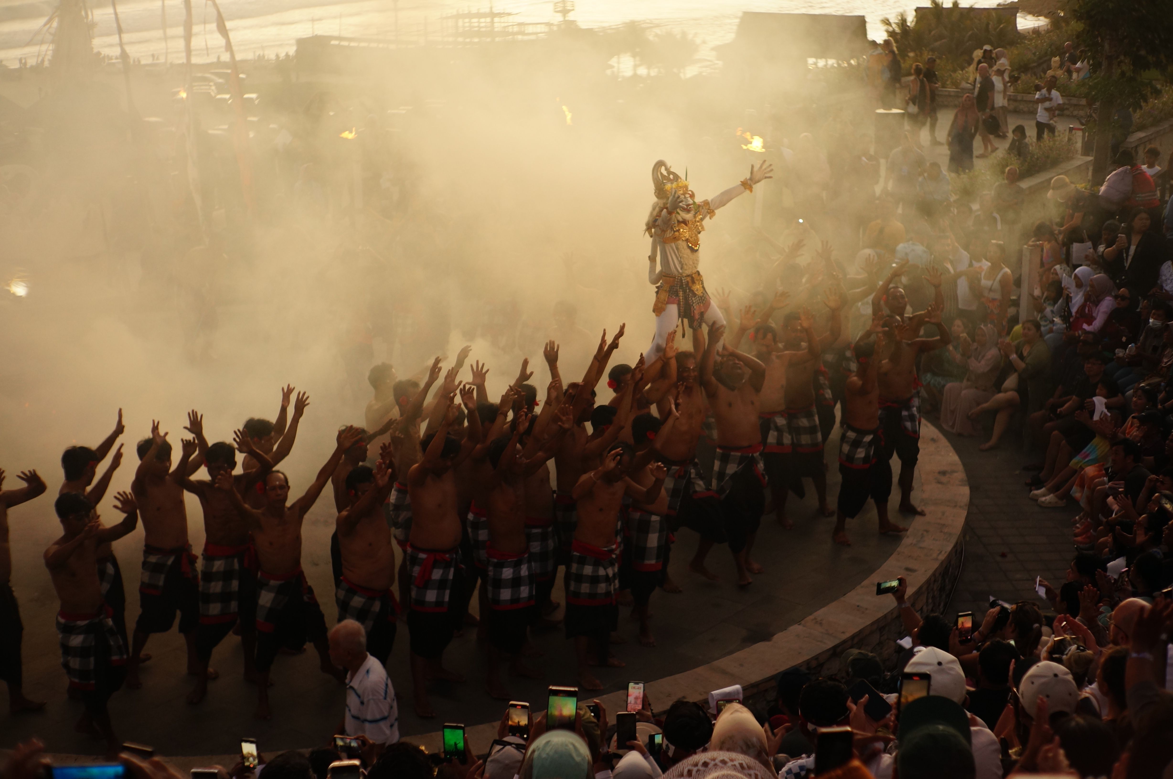 Balinese spectators surrounding a traditional cockfight ring, woven sarongs, tense faces and village temple walls