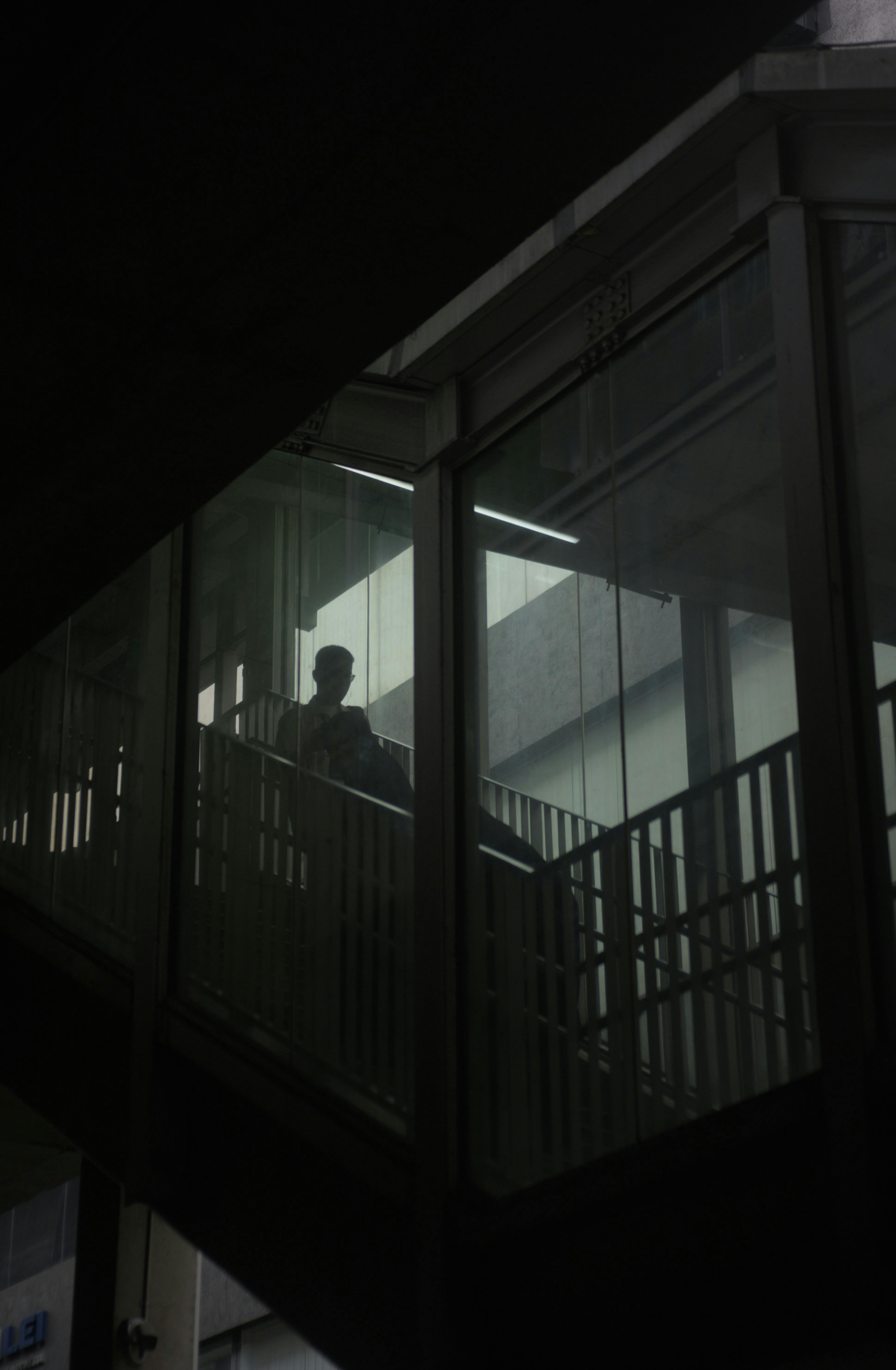 Kostenlos Düstere Silhouette eines Mannes, der auf einer gläsernen Stadttreppe geht und die Einsamkeit einfängt. Stock-Foto