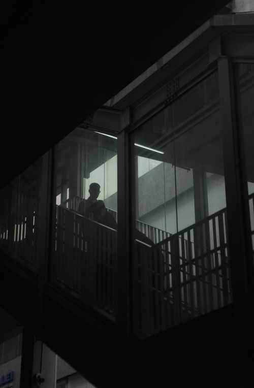 Free Moody silhouette of a man walking on a glass-walled urban staircase, capturing solitude. Stock Photo