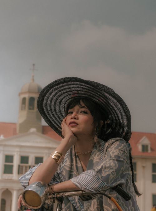 Free Fashionable woman in hat with historic colonial building backdrop Stock Photo