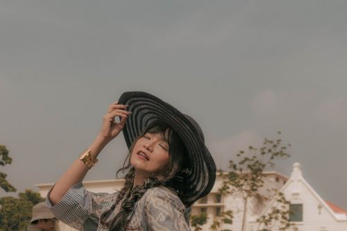 Free A young woman enjoying a sunny day outdoors, wearing a large hat and stylish attire. Stock Photo