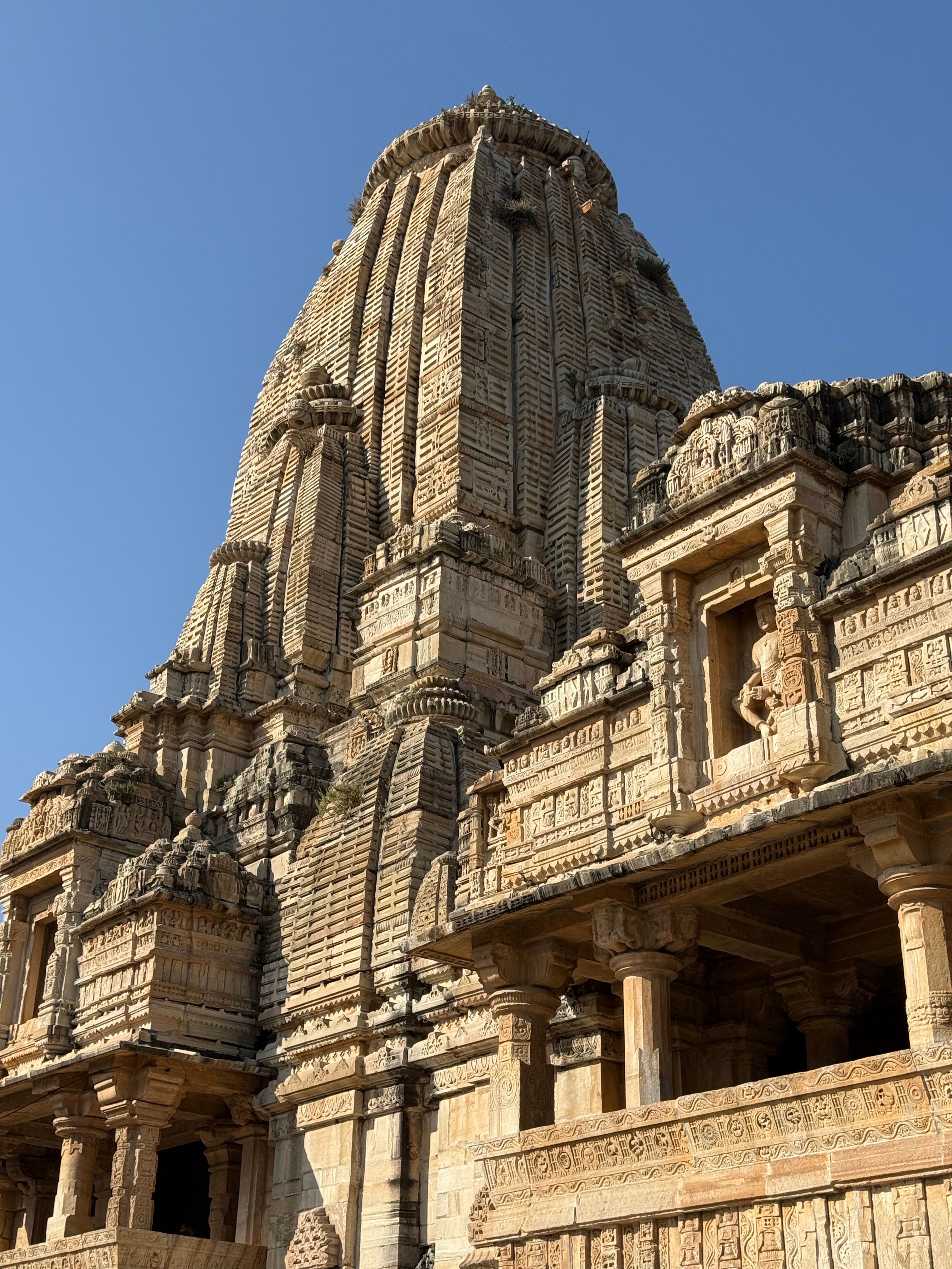 A detailed view of an intricately designed ancient temple under clear blue skies.