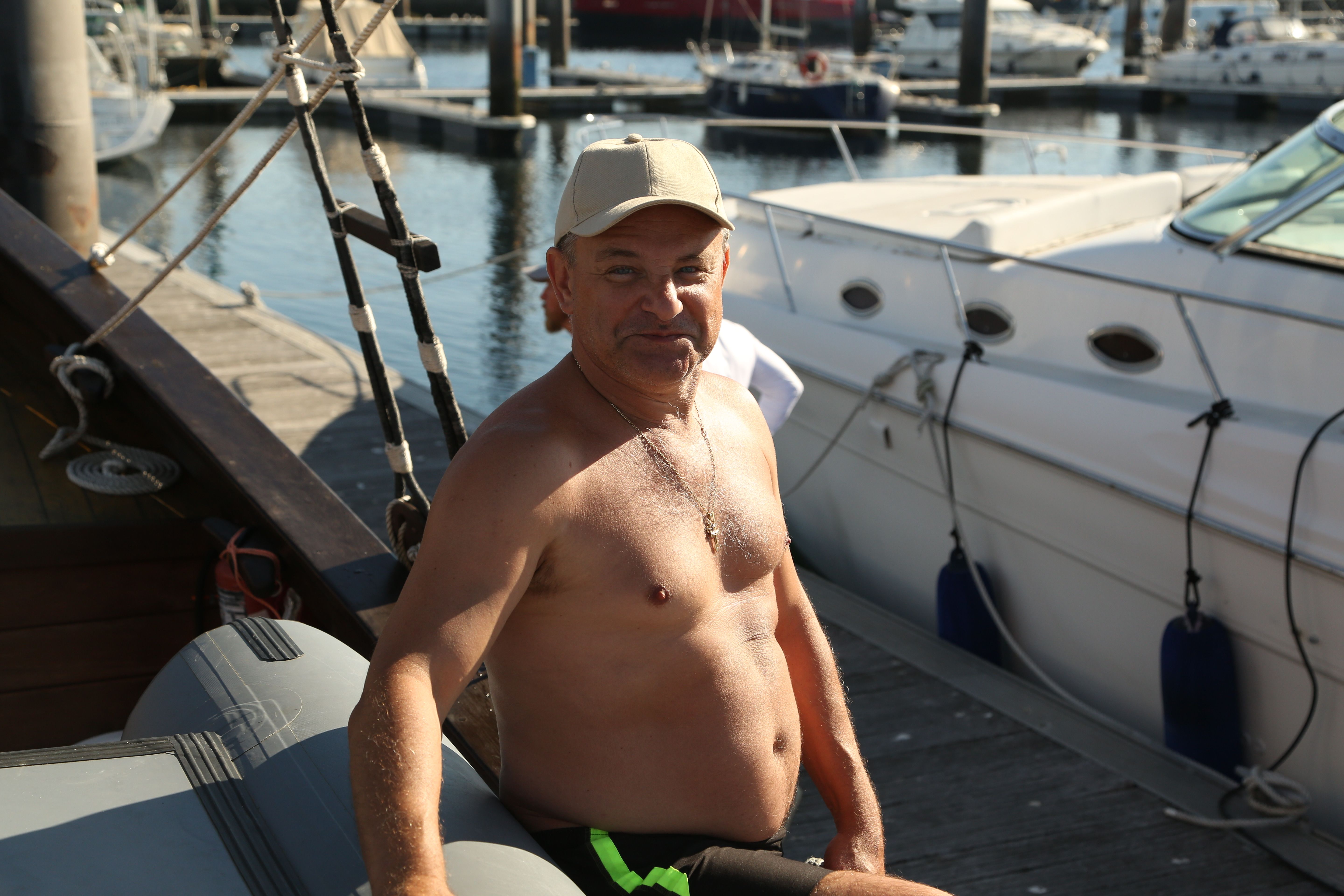 Casual portrait of a man enjoying a sunny day by the marina docks with boats.