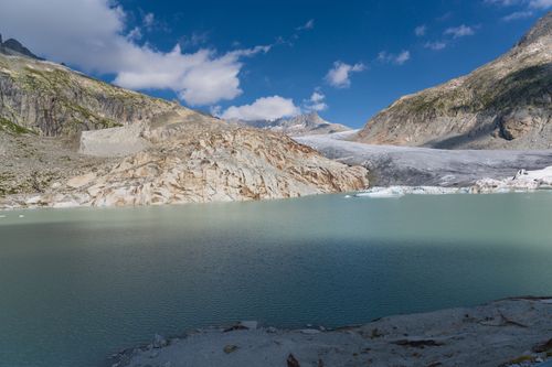 Free A panoramic view of Rhone Glacier with turquoise glacial lake in the Swiss Alps under a clear blue sky. Stock Photo
