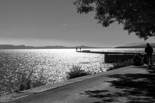 Free A tranquil lakeside view with silhouettes enjoying the sunset in black and white. Stock Photo