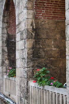 Rustic stone arches with flowering balcony create a picturesque historic charm.