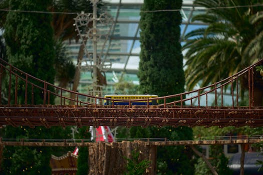 A detailed miniature replica of the Golden Gate Bridge with a model tram in a lush, indoor botanical garden setting.