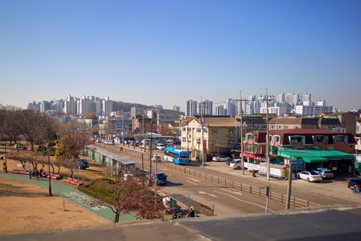 Vibrant cityscape with park view featuring people, buses, and residential buildings.