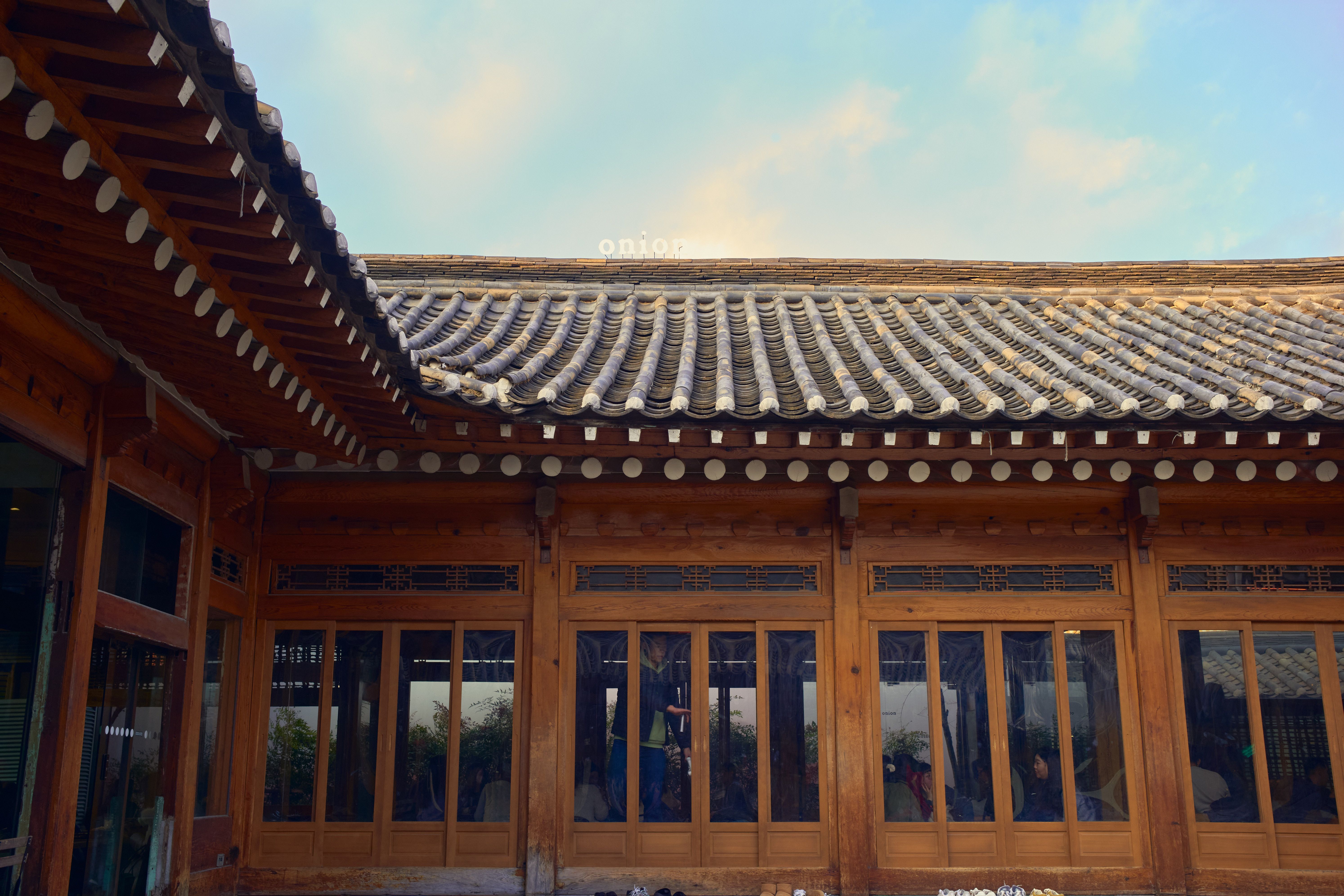 Charming traditional Korean building with wooden architecture and tile roof under a blue sky.