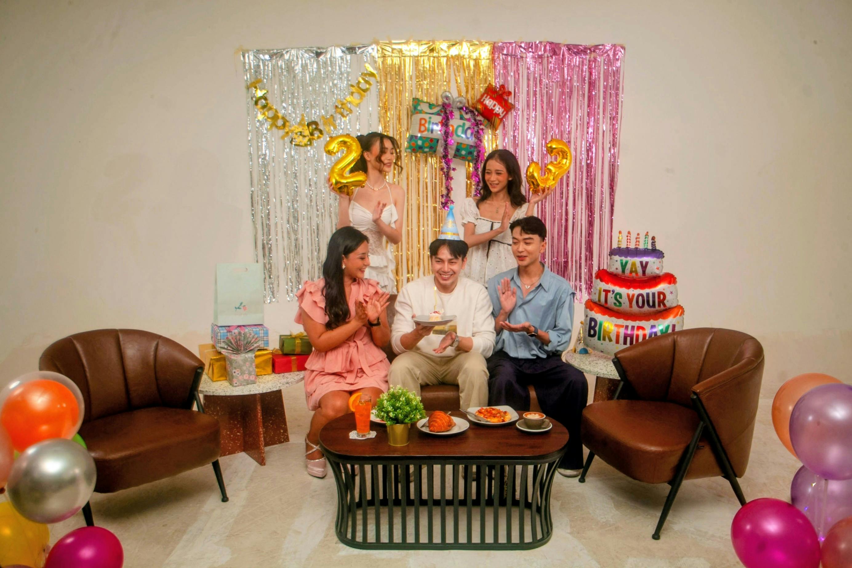 Gratis Amici che si divertono a una vivace festa di compleanno al chiuso, con decorazioni e torta. Foto a disposizione