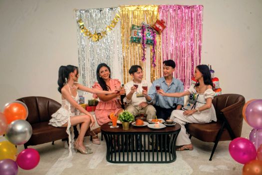 Group of friends enjoying a festive indoor birthday party with decorations and food.
