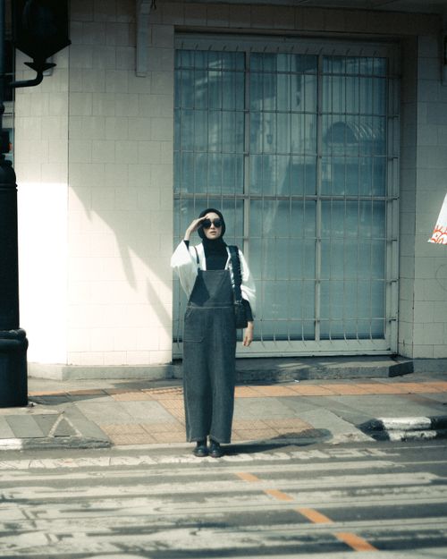 Free A young woman in a hijab stands on an urban street wearing sunglasses. Stock Photo