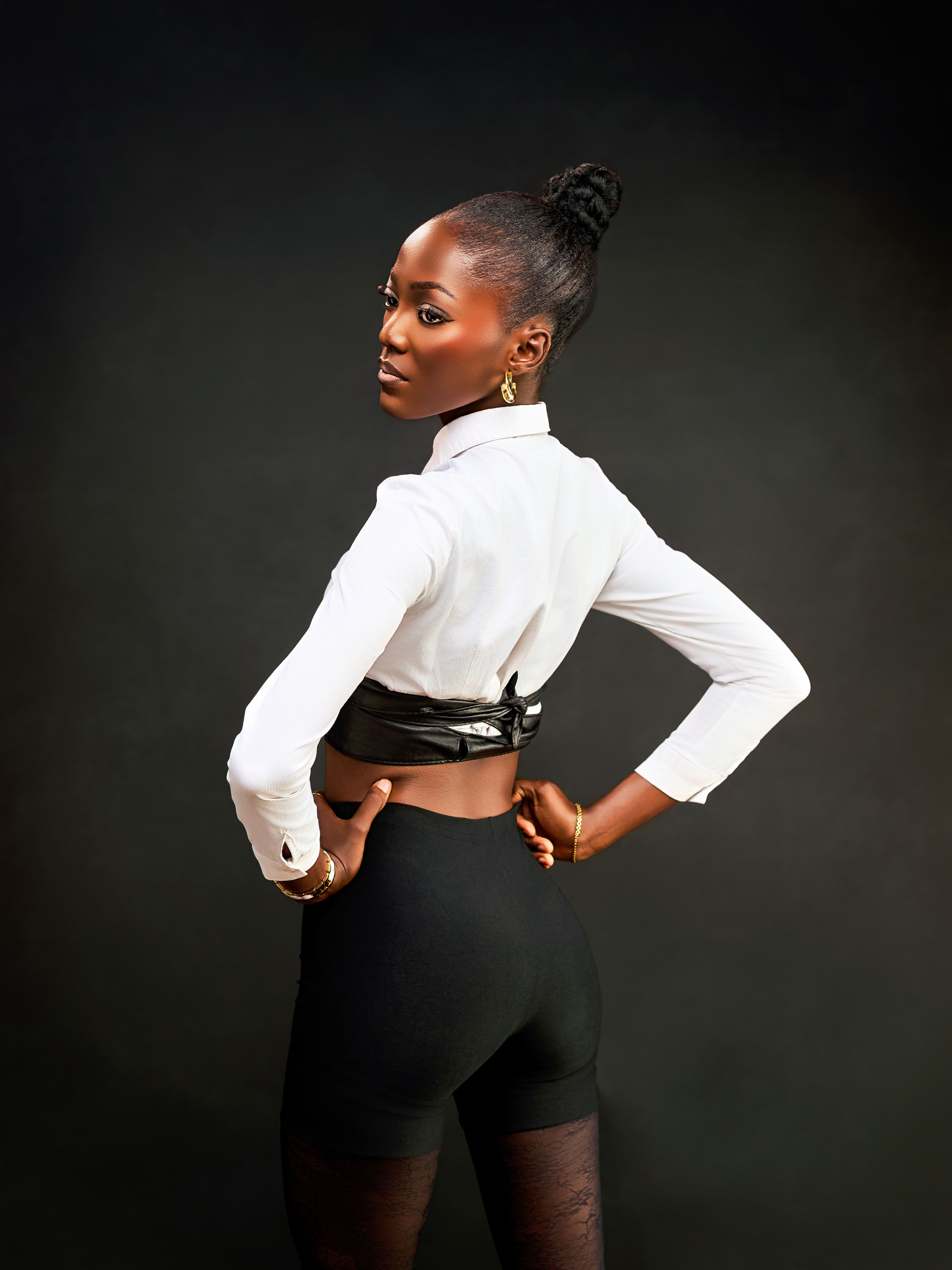 Elegant woman in stylish pose with chic fashion attire on dark background.