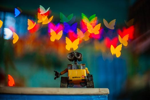 Wall-E toy figurine with vibrant butterfly bokeh lights in the background, creating a whimsical atmosphere.
