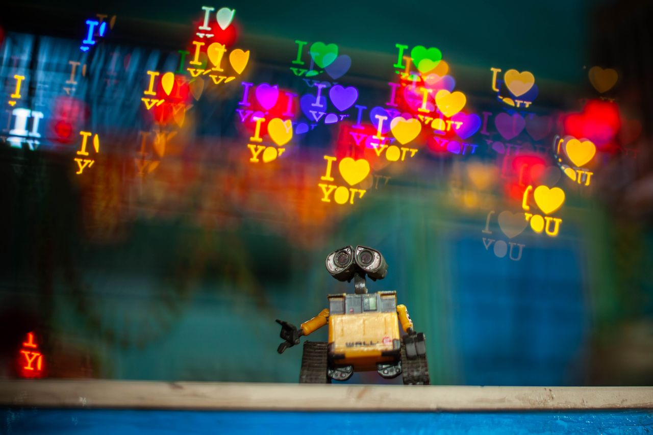 toy robot with colorful bokeh heart shapes and i love you text creatin