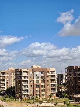 Contemporary apartment complex with bright blue sky and clouds.