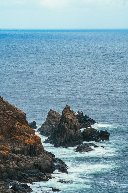 Free Majestic view of rugged cliffs meeting the vast ocean under a clear sky. Stock Photo