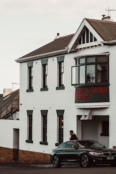 Street view of a historic hotel with a luxury car parked in front, captured in urban setting.