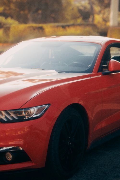 Free Close-up of a sleek red sports car parked outdoors, exuding modern style. Stock Photo