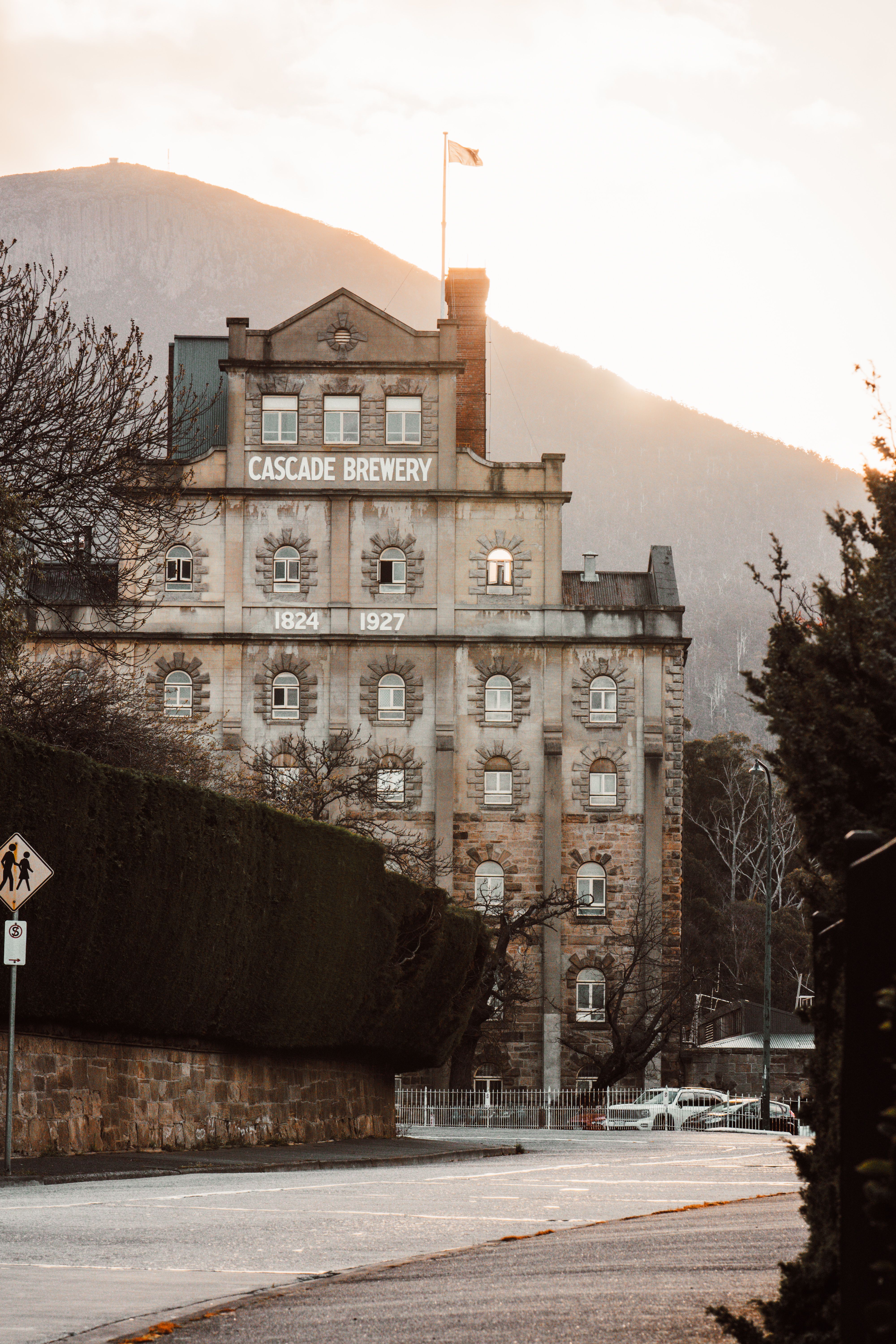 The iconic Cascade Brewery in Hobart, Australia, framed by Mount Wellington during a scenic sunset.