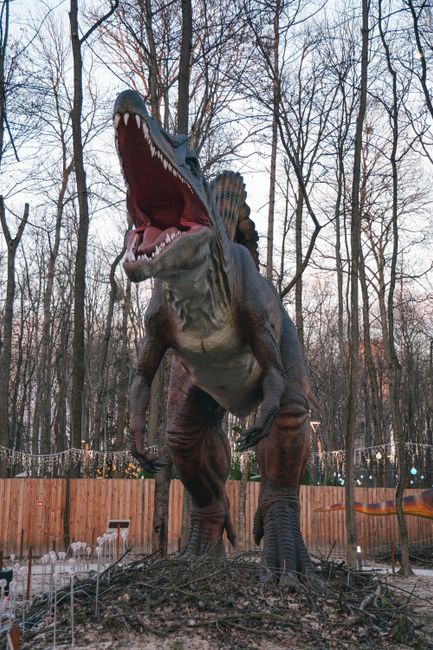 A lifelike dinosaur sculpture stands tall among the trees in Kyiv's park.