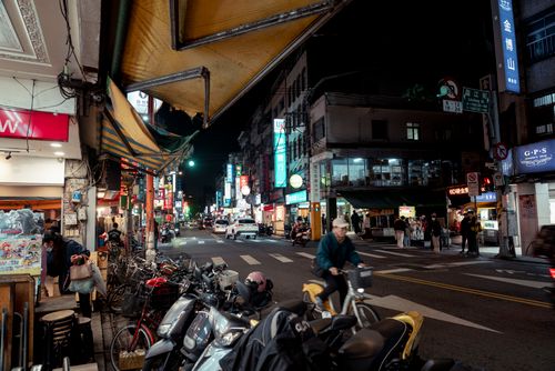 Free A lively Taipei street at night, featuring cyclists, pedestrians, and vibrant shop signs. Stock Photo