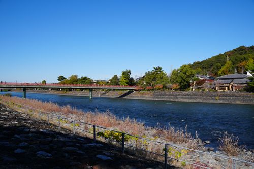 Free Beautiful autumn landscape of Uji River and bridge in Kyoto, Japan, showcasing vibrant foliage and serene water. Stock Photo