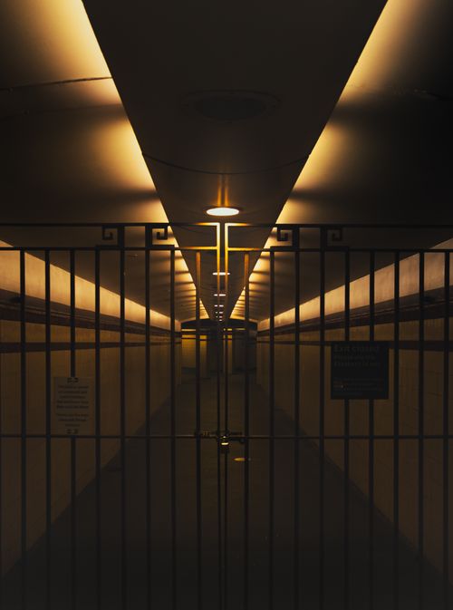 Free Moody underground passageway with closed iron gate and warm lighting. Stock Photo