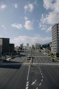 A wide-angle view of a busy city intersection under a clear blue sky with modern buildings.
