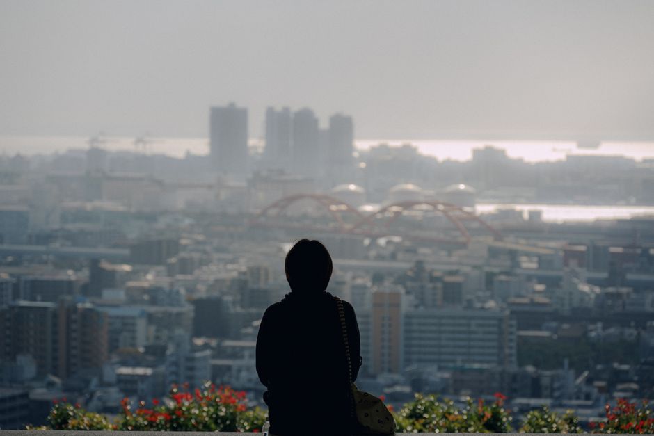 夕暮れ時に、人が上空から広がる都市の景観を眺め、静かなシルエットを作り出します。