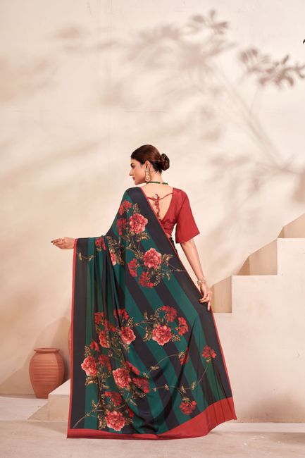 A woman in a floral saree poses elegantly on a stylish staircase indoors.
