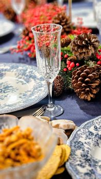 Festive table setting with pine cones, berries, and elegant china. Perfect for holiday gatherings.