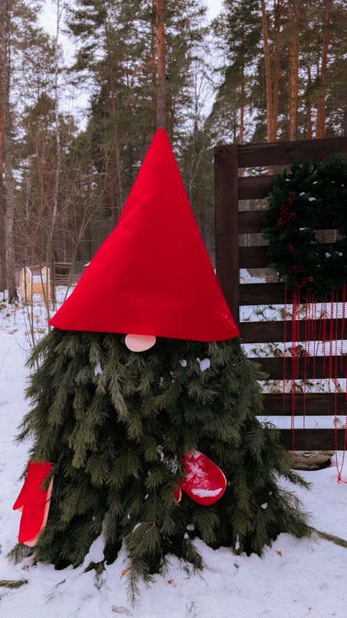 Free Festive outdoor Christmas gnome with red hat and greenery in snowy setting. Stock Photo