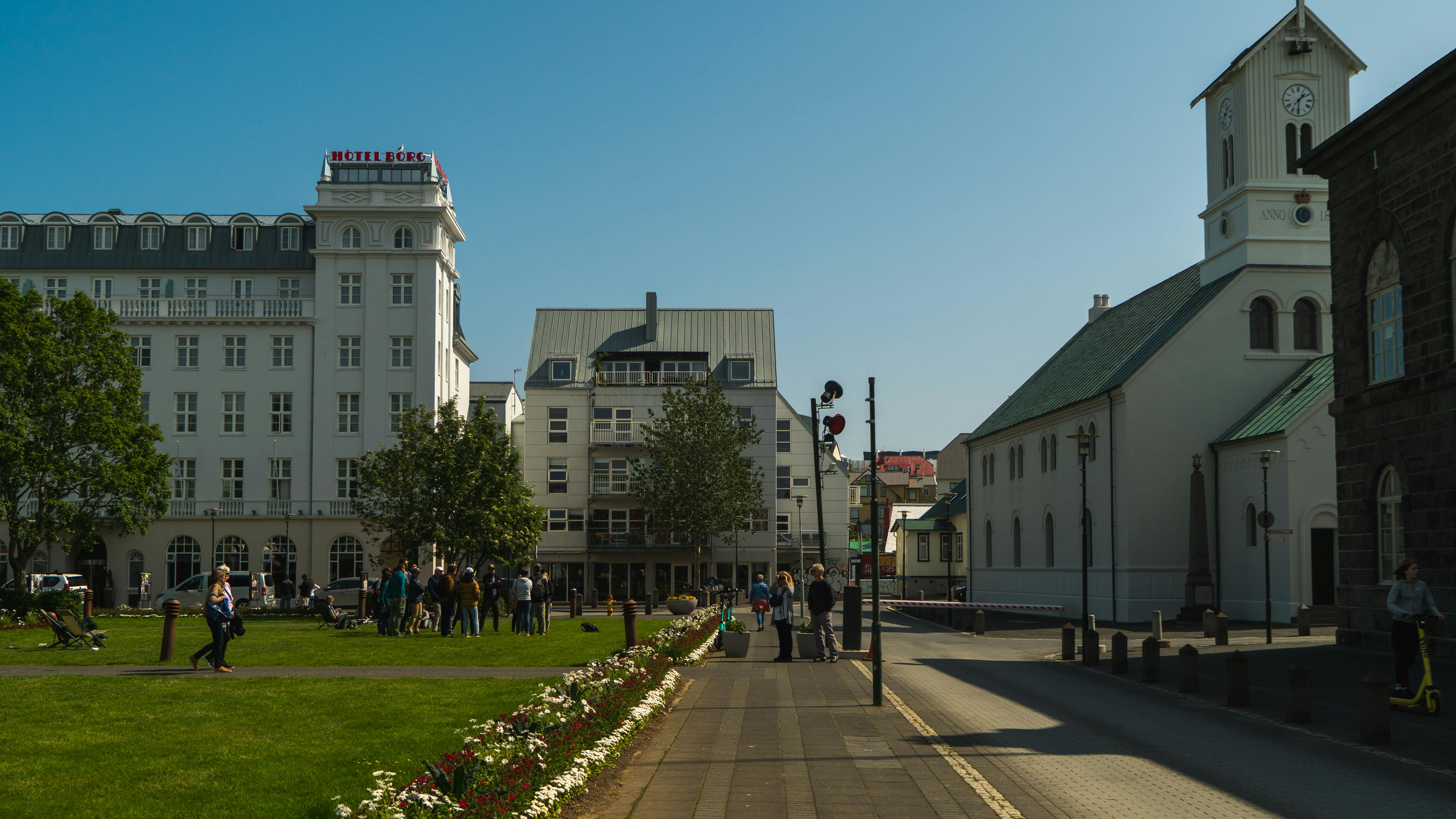 A vibrant daytime street view in Reykjavik with landmarks and people enjoying the sunny weather.