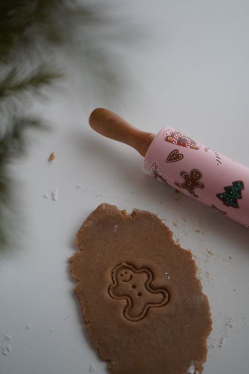 Free Gingerbread dough with cookie cutout, pink festive rolling pin on white surface. Stock Photo