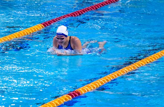 Competitive swimmer in action during a breaststroke event in an indoor pool.
