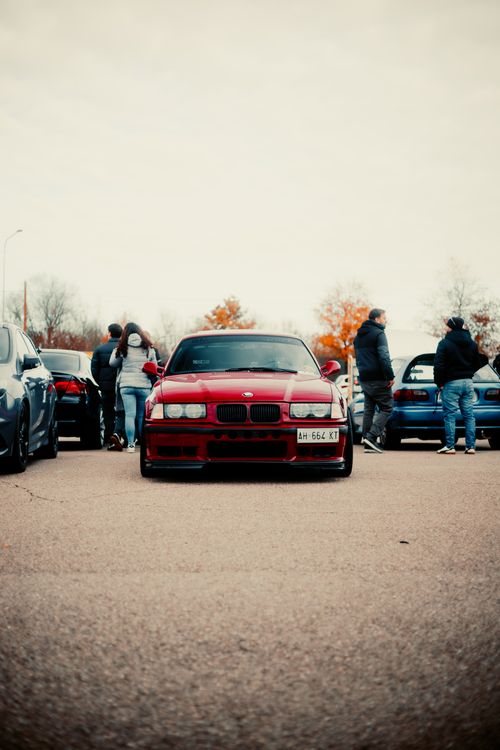 Free Red sports car showcased at an outdoor car gathering with people in the background. Stock Photo