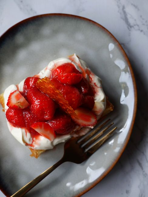 An appetizing strawberry dessert served with cream on a stylish plate, perfect for food lovers.