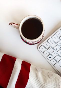 Flat lay of a festive coffee mug with a cozy sweater and keyboard, perfect for holiday mood.