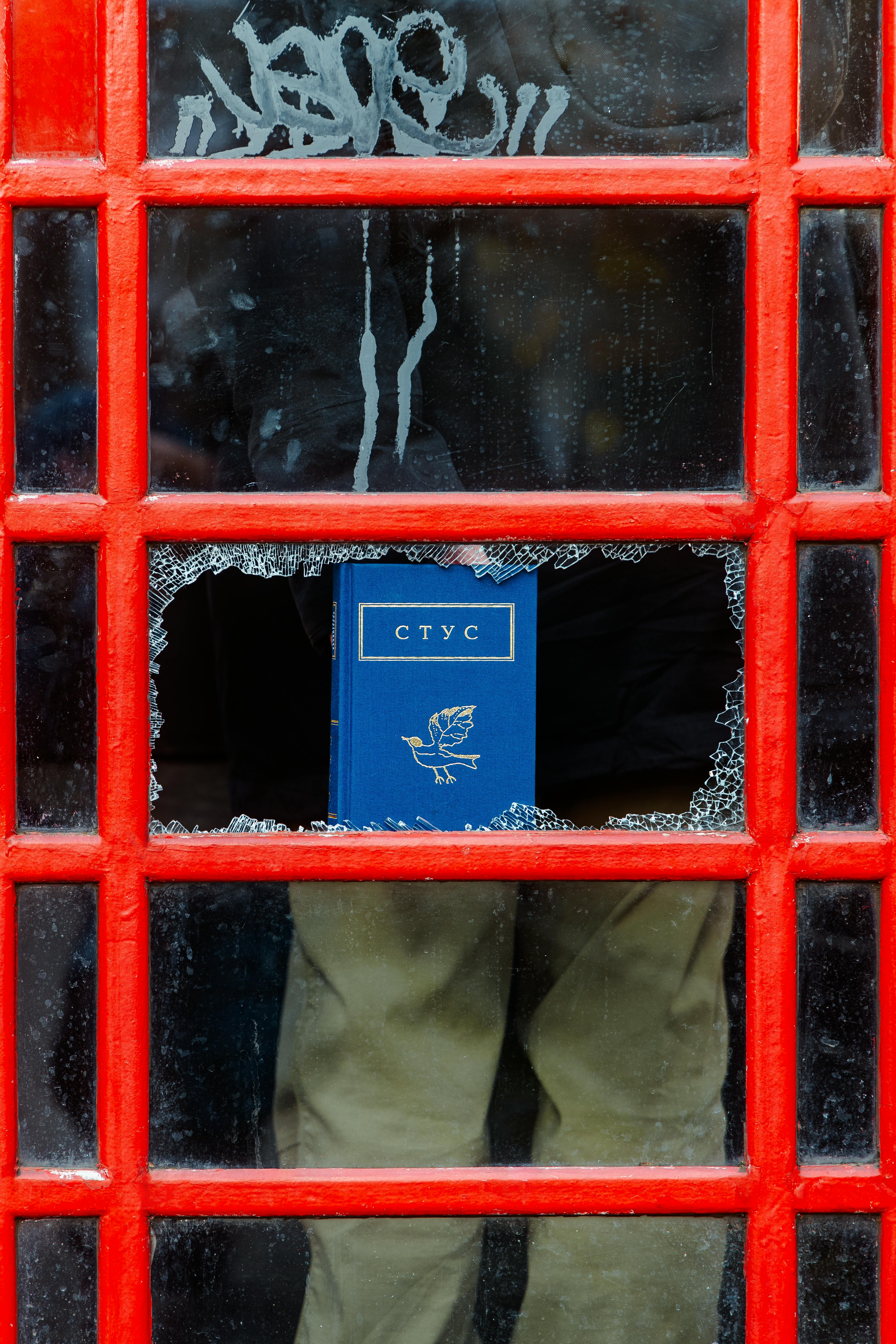 무료 런던의 빨간색 공중전화 부스. 깨진 유리 조각과 그 안에 책이 보인다. 스톡 사진