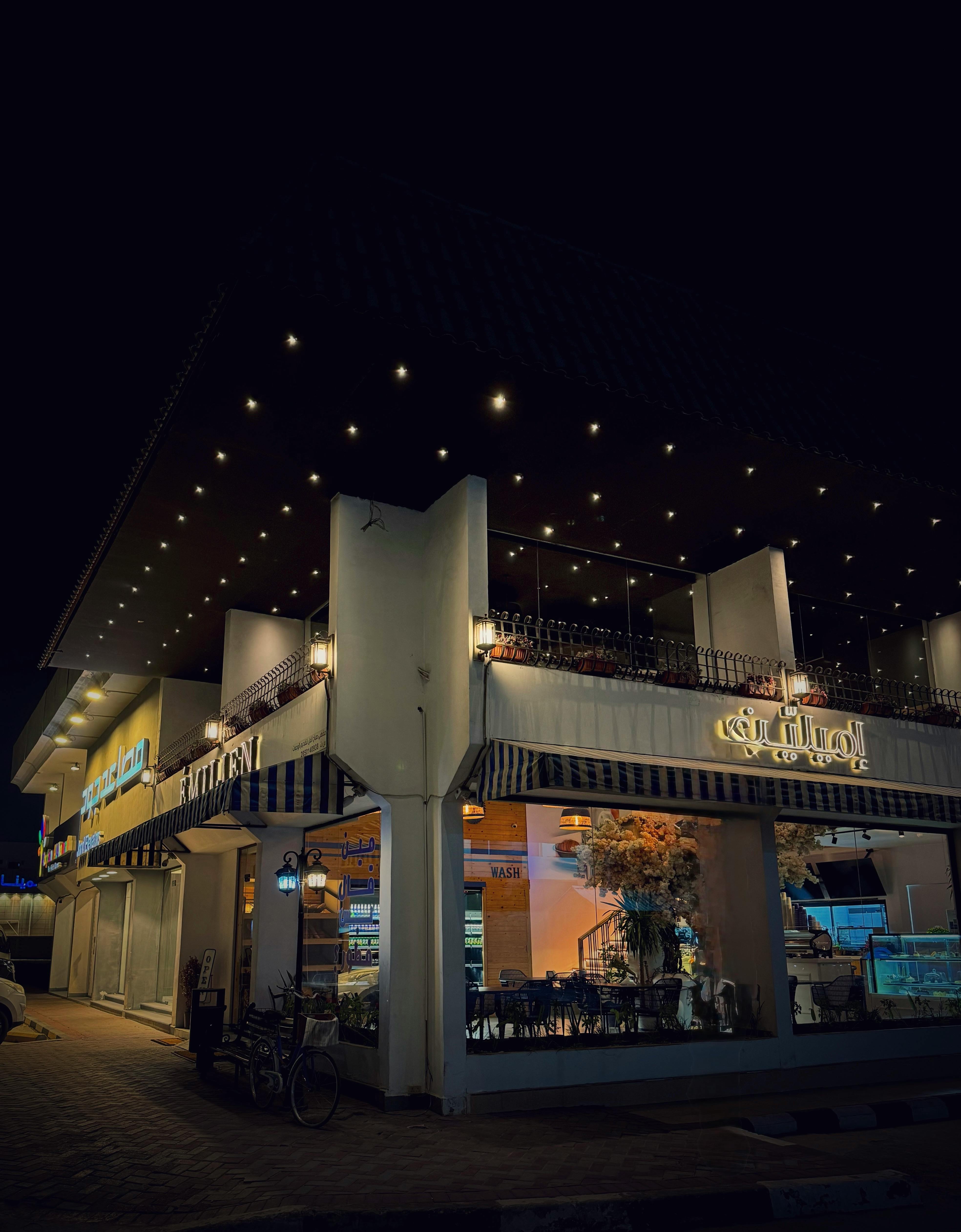 Beautifully lit cafe exterior with modern design and warm ambiance, captured at night.