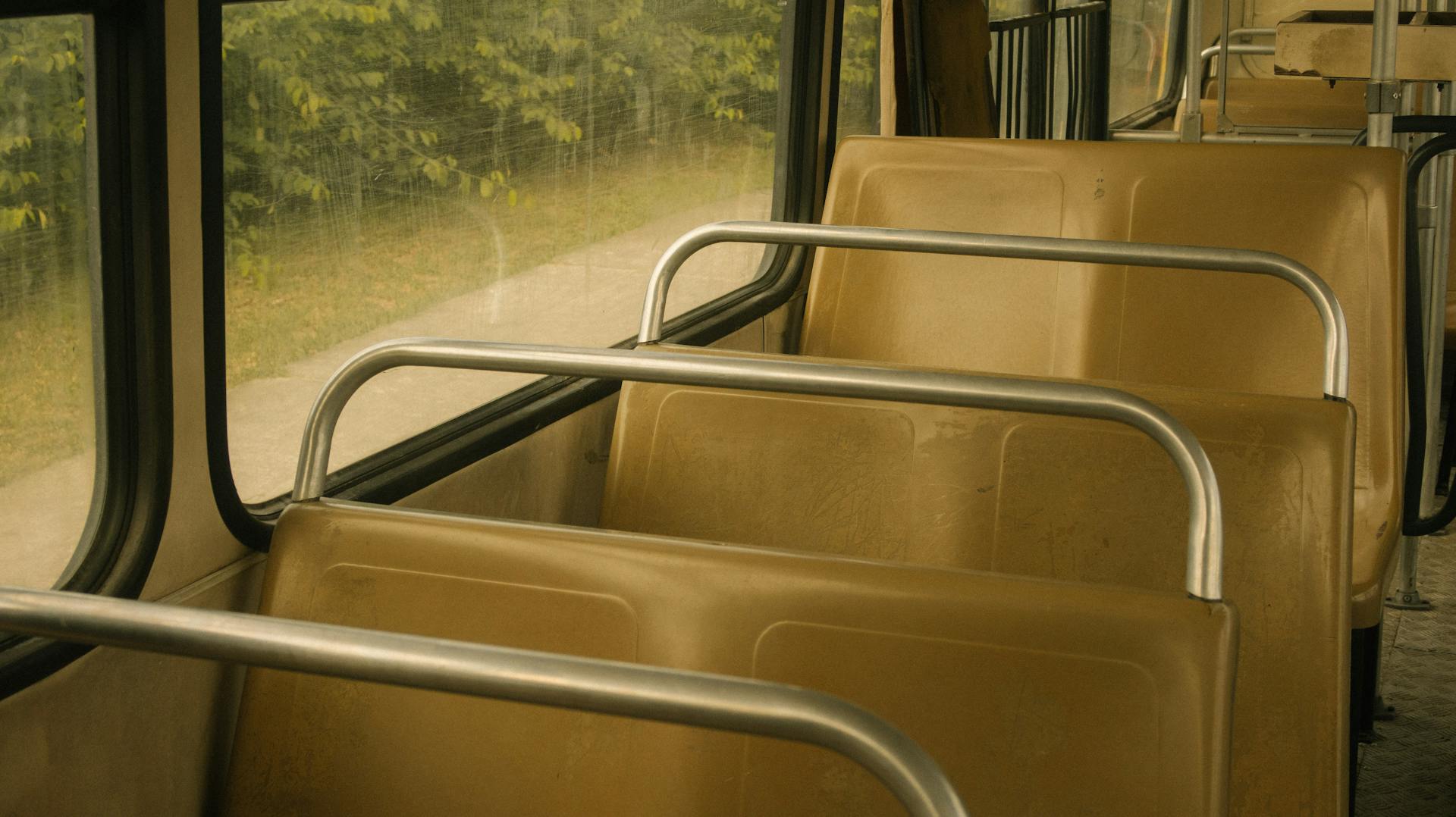 Utforska den lugna och klassiska interiören i en tom offentlig buss med rader av sittplatser.