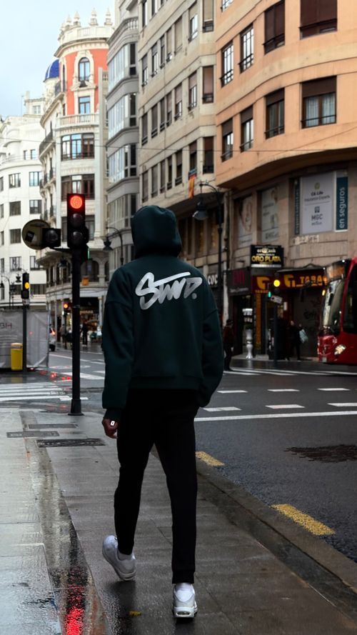 Free Man in hoodie walks through bustling city street, capturing urban lifestyle. Stock Photo
